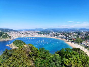 High angle view of city by sea against blue sky