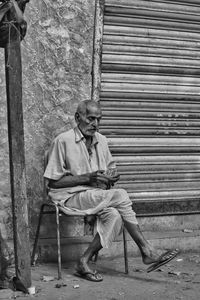 Full length of man sitting against wall