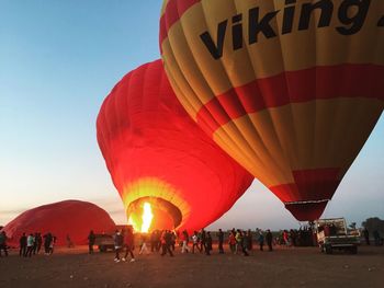 People around hot air balloons against sky