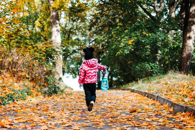 Rear view of woman running on footpath during autumn