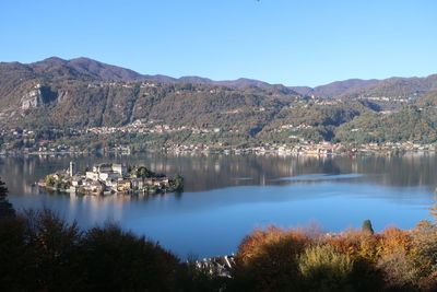 Scenic view of lake and mountains against clear blue sky