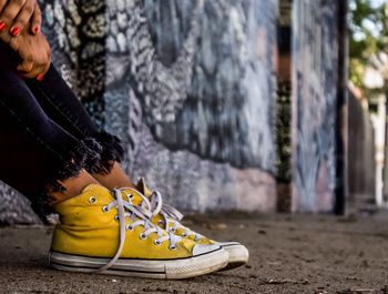 Low section of woman wearing yellow canvas shoes on footpath 