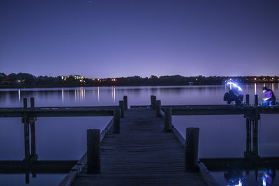 Pier over lake against clear sky at night