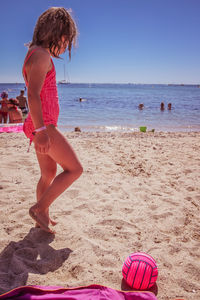 Woman with umbrella on beach against sky