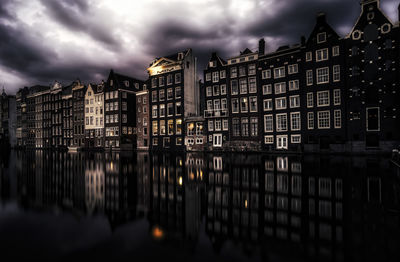 Reflection of houses in water against sky at night