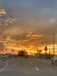 Cars on road against sky during sunset