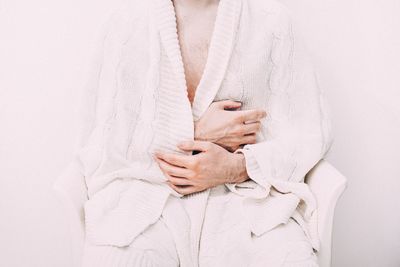 Midsection of man sitting on chair against wall