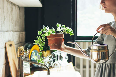Midsection of woman watering potted plant
