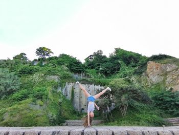 Girl doing handstand on land against sky