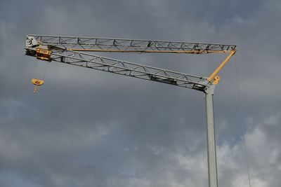 Low angle view of crane against cloudy sky