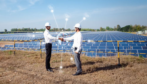 Men standing on field against sky