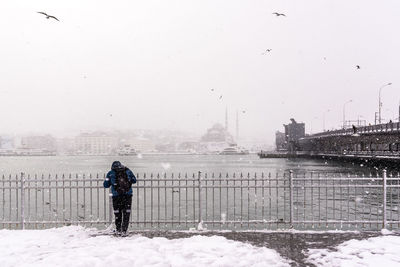 Rear view of man standing on snow against sky