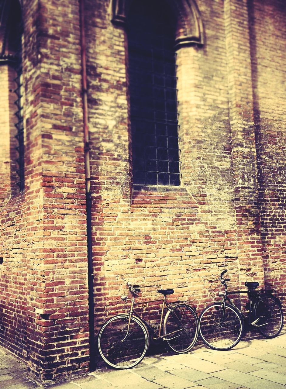 architecture, bicycle, built structure, building exterior, transportation, wall - building feature, brick wall, land vehicle, building, mode of transport, stationary, parked, street, wall, railing, sunlight, parking, window, day, shadow