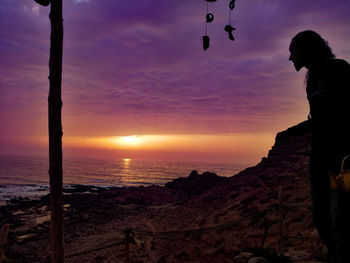 Silhouette man looking at sea against sky during sunset