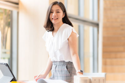 Portrait of a smiling young woman using phone