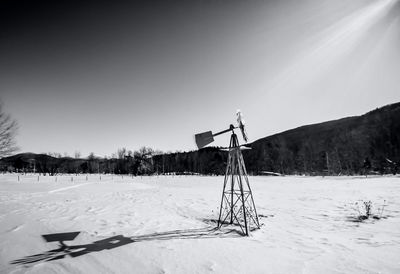 Wind turbines on snow covered field against sky