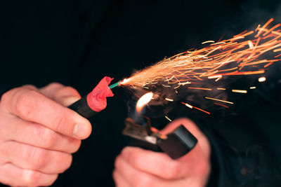 Close-up of hand holding sparkler against blurred background