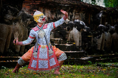 Person in costume dancing against historic wall
