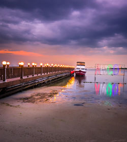 Illuminated bridge over sea against sky during sunset