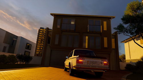 Car on street against buildings in city at sunset
