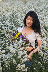 Portrait of beautiful woman standing by flowering plants