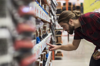 Side view of male customer buying nails from hardware store