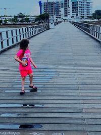 Full length of woman standing on pink umbrella in city