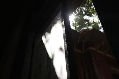 Low angle view of sunlight streaming through window in abandoned building