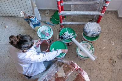 Young woman painting interior wall with white paint. paint cans and painter ladder.