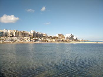 Sea by buildings against sky in city