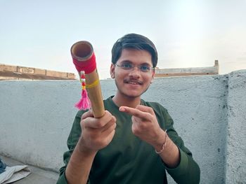 Portrait of young man blowing bubbles against wall
