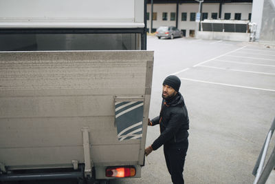 Male worker opening trunk of van while standing on street