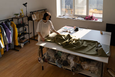 High angle view of woman folding fabric on table