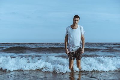 Young man standing in sea on shore at beach