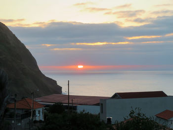 Scenic view of sea and buildings against sky during sunset