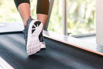 Low section of woman running on treadmill in gym