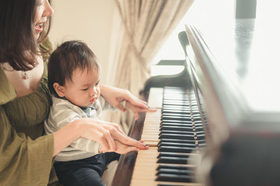 Rear view of friends playing piano