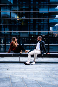 Side view of couple sitting on building