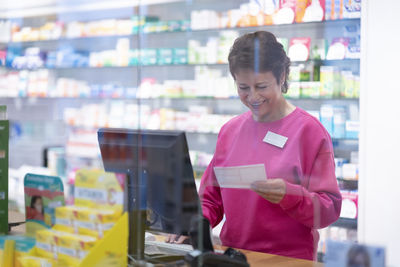 Happy pharmacist examining prescription at medical store