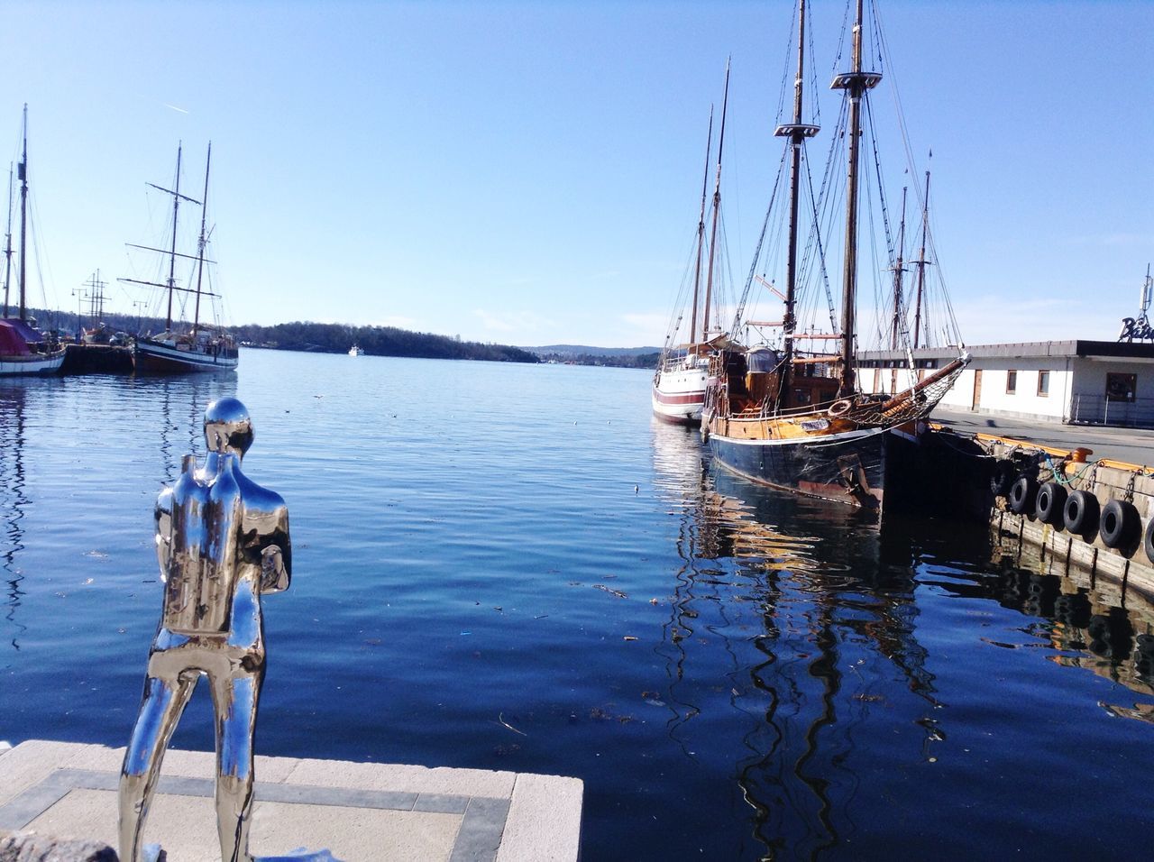 water, nautical vessel, transportation, boat, clear sky, moored, mode of transport, mast, harbor, blue, reflection, sailboat, sea, sky, rope, waterfront, river, rippled, day, lake