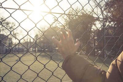 Midsection of person seen through chainlink fence