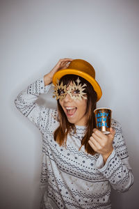 Portrait of woman holding cup against gray background