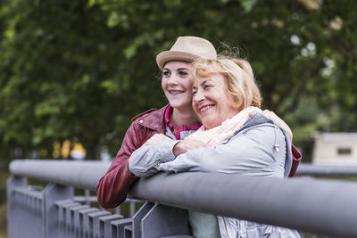 Happy grandmother and granddaughter leaning together on railing