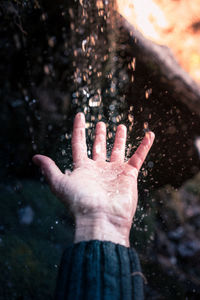 Cropped hand of woman splashing water in lake