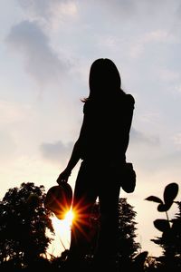 Silhouette woman standing against sky during sunset