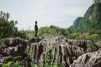 MAN STANDING ON CLIFF AGAINST SKY