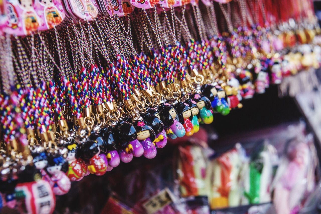 multi colored, variation, abundance, large group of objects, close-up, hanging, selective focus, indoors, choice, still life, in a row, for sale, colorful, arrangement, decoration, focus on foreground, collection, bead, retail, no people