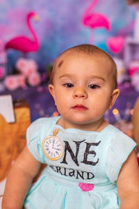 Portrait of cute baby girl sitting on hardwood floor 