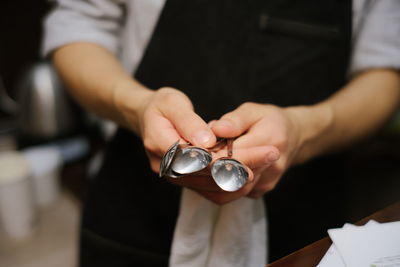 Midsection of waiter holding spoons in restaurant