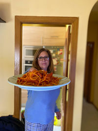 Portrait of woman holding food at home